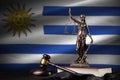 Uruguay flag with statue of lady justice, constitution and judge hammer on black drapery. Concept of judgement and guilt