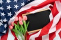US American flag with blackboard and tulip flower on blue wooden background. For USA Memorial day, Presidents day, Veterans day, Royalty Free Stock Photo