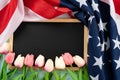 US American flag with blackboard and tulip flower on blue wooden background. For USA Memorial day, Presidents day, Veterans day, Royalty Free Stock Photo