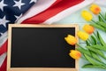 US American flag with blackboard and tulip flower on blue wooden background. For USA Memorial day, Presidents day, Veterans day, Royalty Free Stock Photo