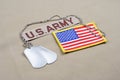 US ARMY branch tape with dog tags and US flag patch on desert camouflage uniform Royalty Free Stock Photo