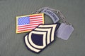 US ARMY Sergeant First Class rank patch, airborne tab, flag patch and dog tag on olive green uni