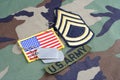 US ARMY Sergeant First Class rank patch, branch tape, flag patch and dog tags on woodland camouflag Royalty Free Stock Photo