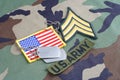 US ARMY Sergeant rank patch, branch tape, flag patch and dog tags on woodland camouflage uniform