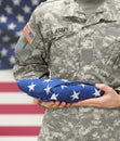 US Army soldier holding folded USA flag before his chest Royalty Free Stock Photo