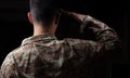 Young soldier saluting standing on black background Royalty Free Stock Photo