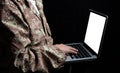 Young soldier working with a laptop computer with blank screen on black background Royalty Free Stock Photo