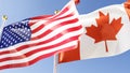 us and canada flags fluttering in the wind against a blue sky, 3d rendering Royalty Free Stock Photo