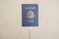 US citizen passport with white cable plugged into the passport on a beige textile backdrop in sunlight