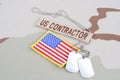US CONTRACTOR branch tape with dog tags and flag patch on desert camouflage uniform Royalty Free Stock Photo