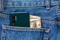 US dollar banknotes and green smartphone in the left rear pocket of blue jeans. Royalty Free Stock Photo