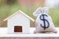 US dollar in a money bag, small residential, house model on table against green nature background. Royalty Free Stock Photo