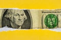 US dollar peeking through torn yellow paper