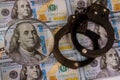 100 US dollars banknotes under magnifying glass of counterfeit money and handcuffs Royalty Free Stock Photo