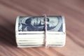 US dollars rolled up and tightened with band isolated on wooden table Royalty Free Stock Photo