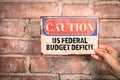 US Federal Budget Deficit. Caution sign in a woman& x27;s hand on a brick background Royalty Free Stock Photo