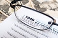 US 1040 individual tax return form closeup with glasses and dollar bills