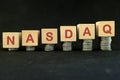 US stock market economy growth and recovery concept. Nasdaq index in wooden blocks with increasing stack of coins in black