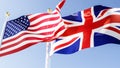 us and uk flags fluttering in the wind against a blue sky, 3d rendering Royalty Free Stock Photo