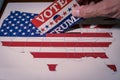 USA elections 2020, the hand of a man putting a vote for trump in a ballot box with the US Map and flag