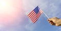 USA flag in hand. Festive USA flag in hand against blue sky and summer natural landscape. American holidays concept. Royalty Free Stock Photo