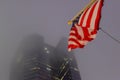 USA Flag Waving in the Wind with a Low Angle View of a Skyscraper in Background. New York City Manhattan on a Foggy Night Royalty Free Stock Photo