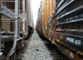 Picture taken between two trains, containers covered in graffiti and gravel floor