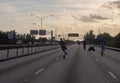 Bike riders drive recklessly on road in front of sign that reads don`t text and drive