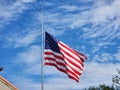 USA national flag waving lowered to half mast on wind against blue sky. American stars and stripes spangled banner as