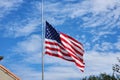 USA national flag waving lowered to half mast on wind against blue sky. American stars and stripes spangled banner as