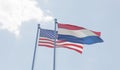 USA and Netherlands flags waving against blue sky. Royalty Free Stock Photo