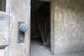 Close up of corroded green door handle and the entrance to a dark stairway in an abandoned building