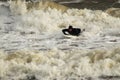 Surfer in the black swimsuit swimming lying on a white surfing board in the stormy ocean Royalty Free Stock Photo