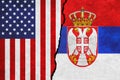 USA and Serbia painted flags on a wall with a crack. United States of America and Serbia relations.