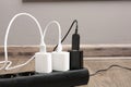 USB adapters with charge cables in power strip on floor indoors, closeup Royalty Free Stock Photo
