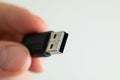 USB cable connector plug close up shot held between fingers by Caucasian male hand isolated against white Royalty Free Stock Photo