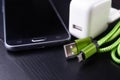 A usb cable for data transfer and phone charging. Telephone and accessories on the table Royalty Free Stock Photo