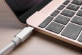 USB cable plugged into laptop port on light wooden table, closeup Royalty Free Stock Photo