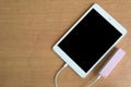 USB cable power bank with tablet on wood desk Royalty Free Stock Photo