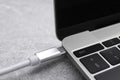 USB cable with type C connector plugged into laptop port on grey table Royalty Free Stock Photo