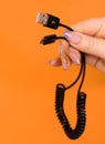 USB computer connector in a girl`s hand on a orange background