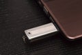 USB metal flash drive connected by hand to a laptop