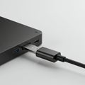 A USB Type-C cable is inserted into a sleek, black electronic device, possibly a laptop Royalty Free Stock Photo