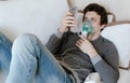 Use nebulizer and inhaler for the treatment. Young man inhaling through inhaler mask lying on the couch and chatting in