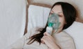 Use nebulizer and inhaler for the treatment. Young woman inhaling through inhaler mask lying on the couch. Closeup front Royalty Free Stock Photo