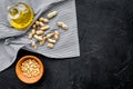 Use nut oil as cosmetics. Peanut oil in jar near peanut in bowl on blue tablecloth on black background top view copy Royalty Free Stock Photo