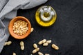 Use nut oil as cosmetics. Peanut oil in jar near peanut in bowl on black background top view copy space Royalty Free Stock Photo