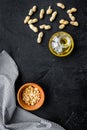 Use nut oil as cosmetics. Peanut oil in jar near peanut in bowl on black background top view copy space Royalty Free Stock Photo