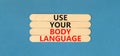 Use your body language symbol. Concept words Use your body language on wooden stick. Beautiful blue table blue background.