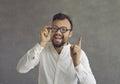 Funny crazy looking nerd in glasses has a brilliant idea and points his finger up Royalty Free Stock Photo